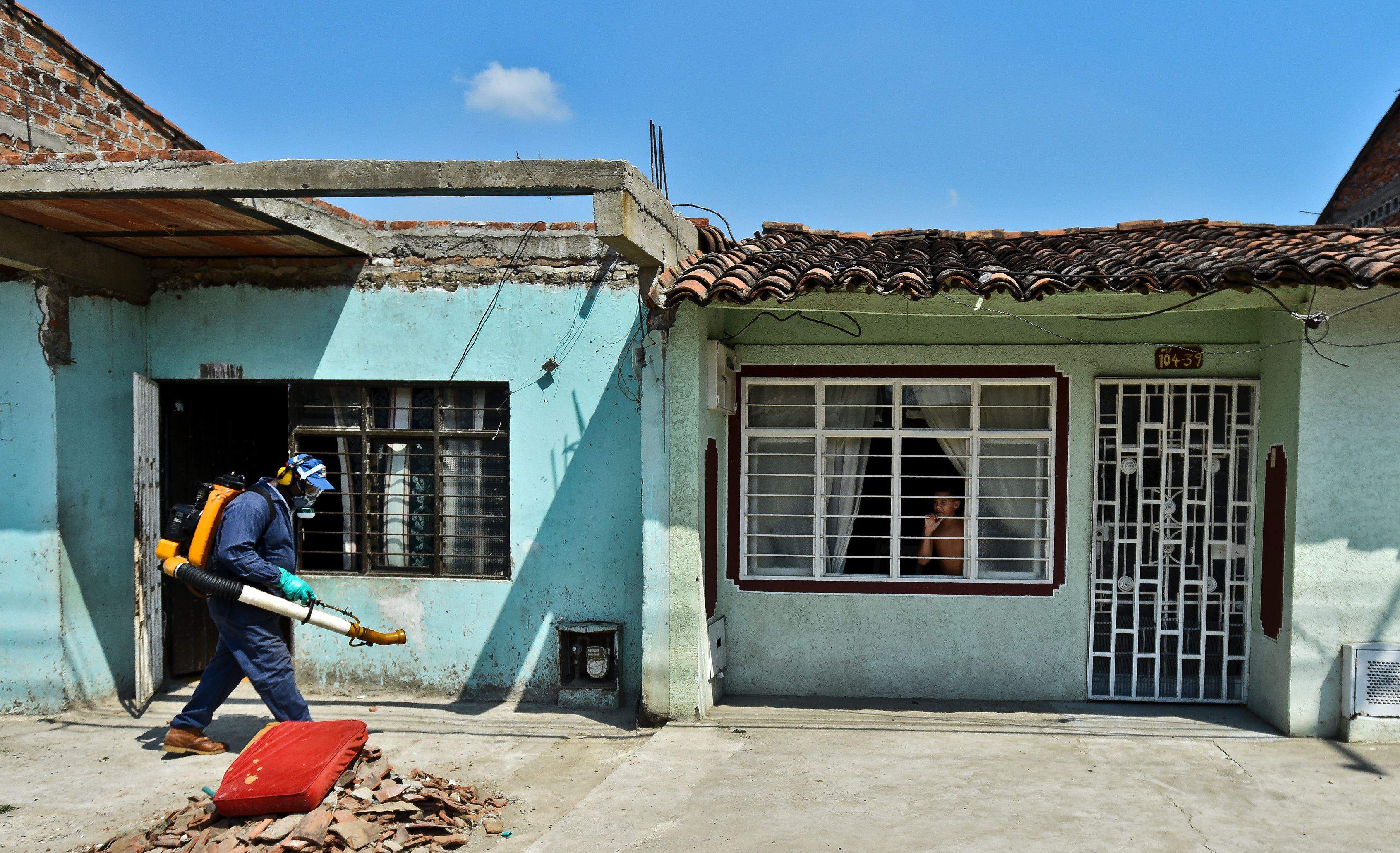 Un empleado de la Secretaría de Salud fumiga contra el mosquito Aedes Aegypti fuera de las casas de Cali, Colombia. (Getty)