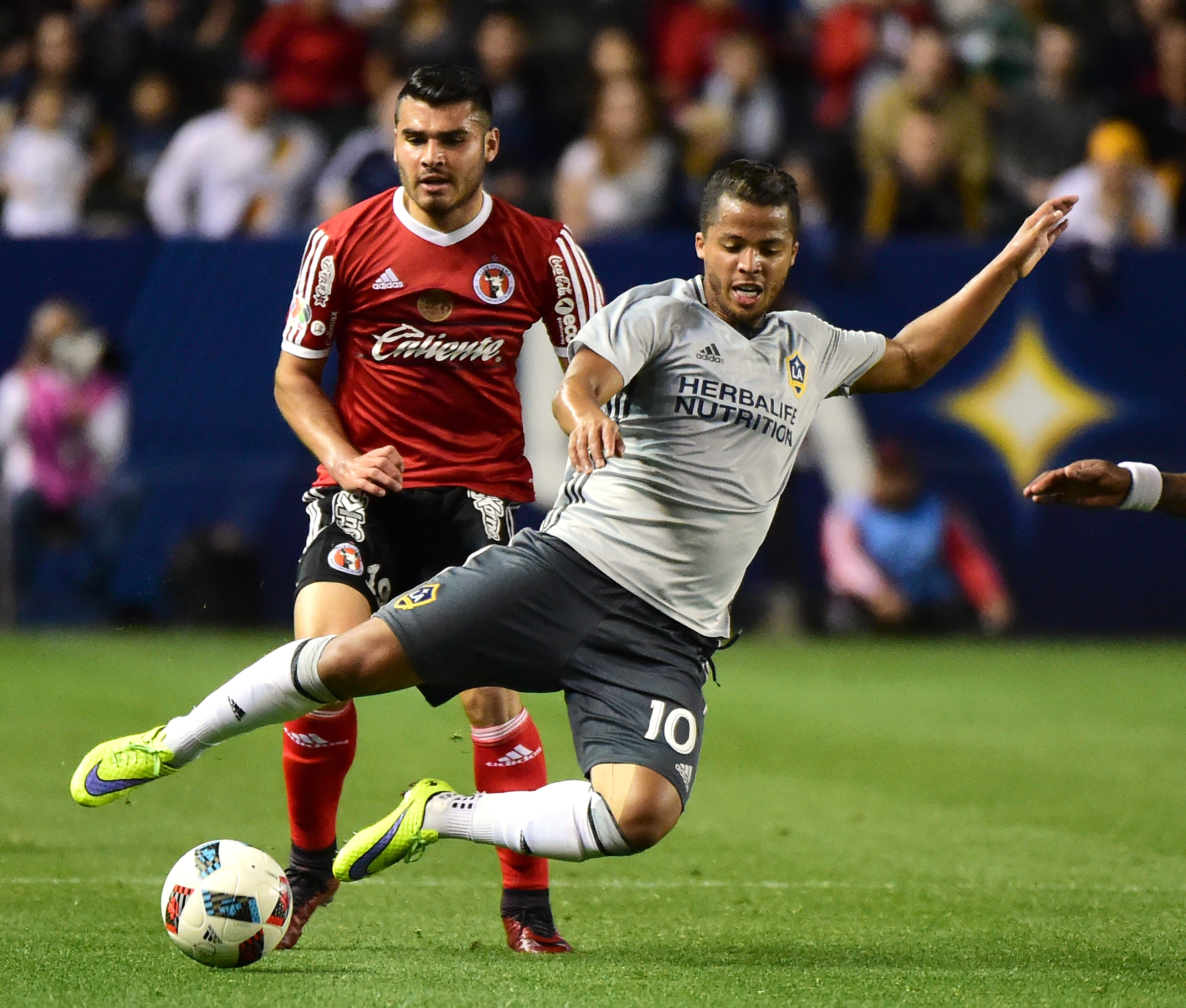 CARSON, CA - FEBRUARY 09: Giovani Dos Santos #10 of Los Angeles Galaxy is tripped by Alberto Garcia #19 of Club Tijuana during the second half at StubHub Center on February 9, 2016 in Carson, California. (Photo by Harry How/Getty Images)