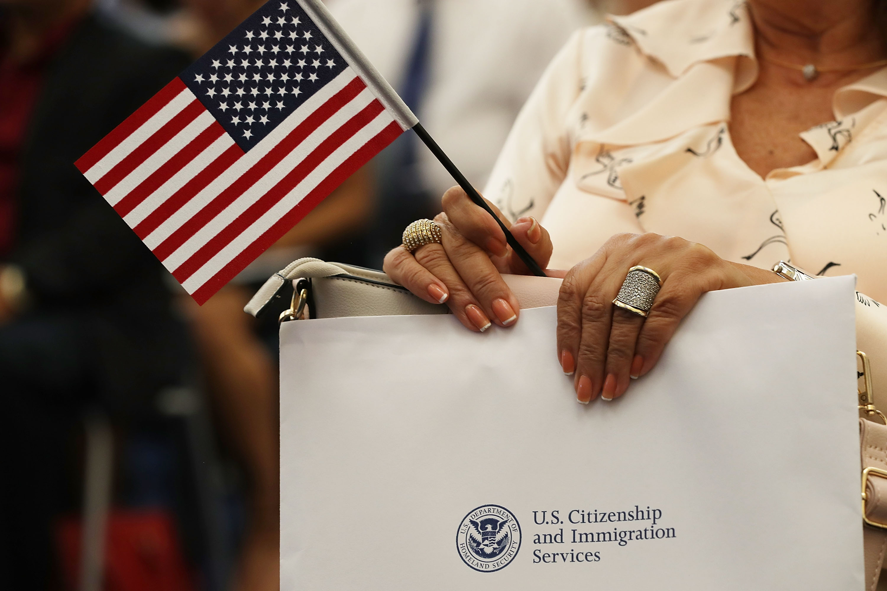 Una persona sostiene una bandera estadounidense mientras participan en la ceremonia para convertirse en ciudadano  durante la naturalización del Servicio de Inmigración en la Oficina de Campo de Miami el 17 de agosto de 2018 en Miami, Florida.