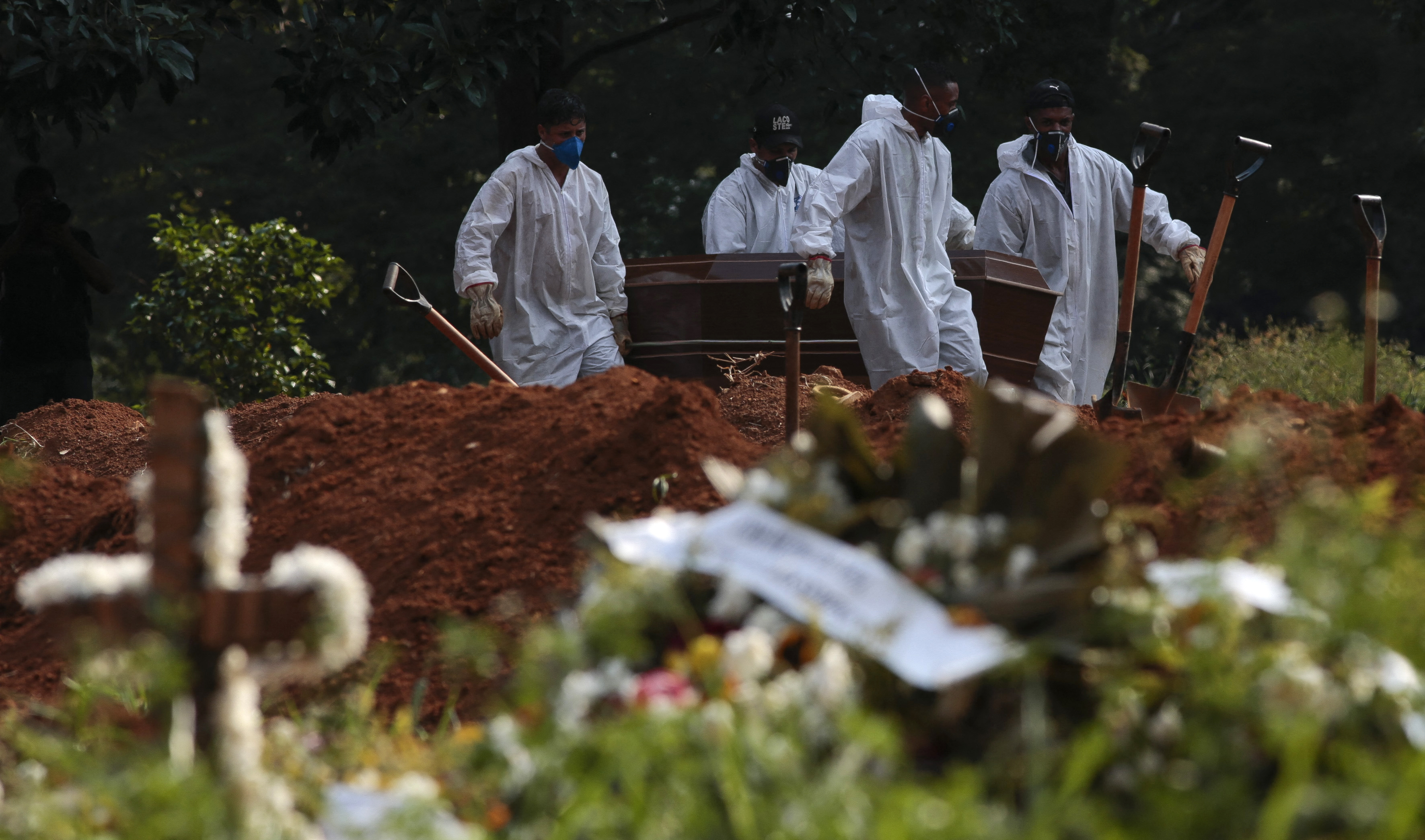 Los trabajadores del cementerio llevan el ataúd de una víctima de COVID-19 en el cementerio de Vila Formosa en Sao Paulo, Brasil, el 23 de marzo de 2021.