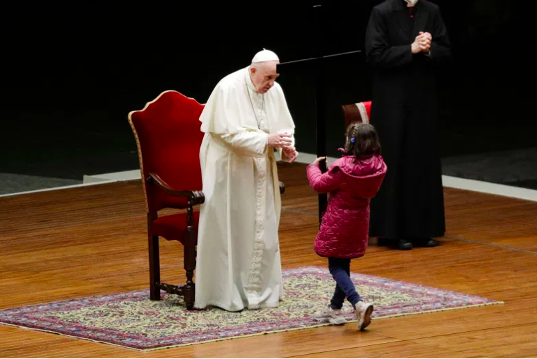 Una niña lleva la cruz al Papa Francisco mientras dirige la celebración del Vía Crucis como parte del Viernes Santo el 2 de abril de 2021 en la plaza de San Pedro en el Vaticano.