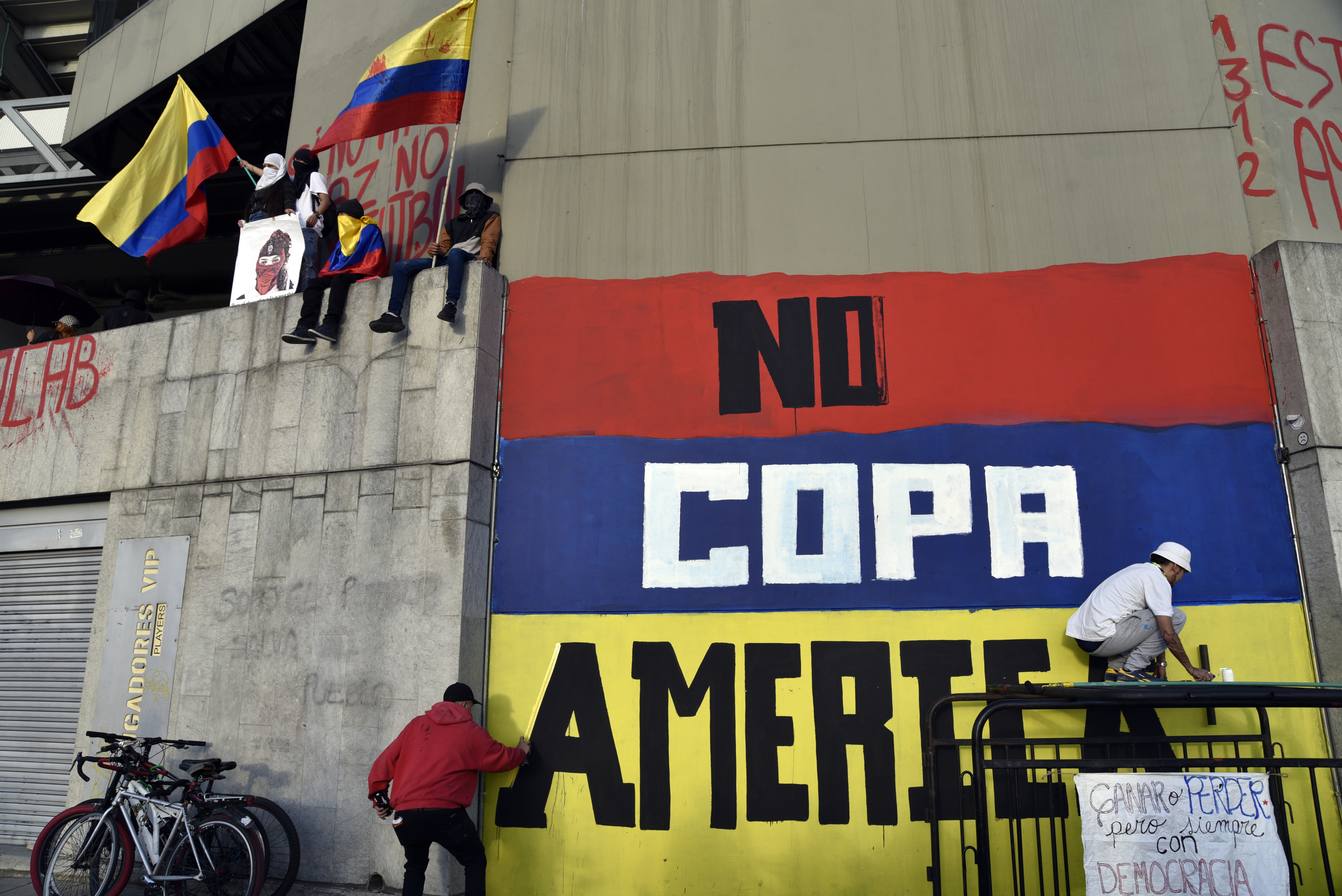 Artistas callejeros pintan un graffiti contra Colombia como anfitri&oacute;n de la Copa Am&eacute;rica en una pared del Estadio Campin durante una protesta como parte de una huelga nacional el 19 de mayo de 2021 en Bogot&aacute;, Colombia.