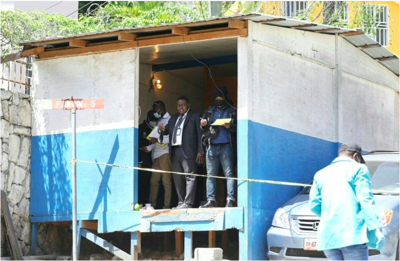 El juez Carl Henry Celestin (C) habla con miembros de la policía y forenses haitianos en la entrada de la residencia presidencial el 7 de julio de 2021 en Puerto Príncipe, Haití.