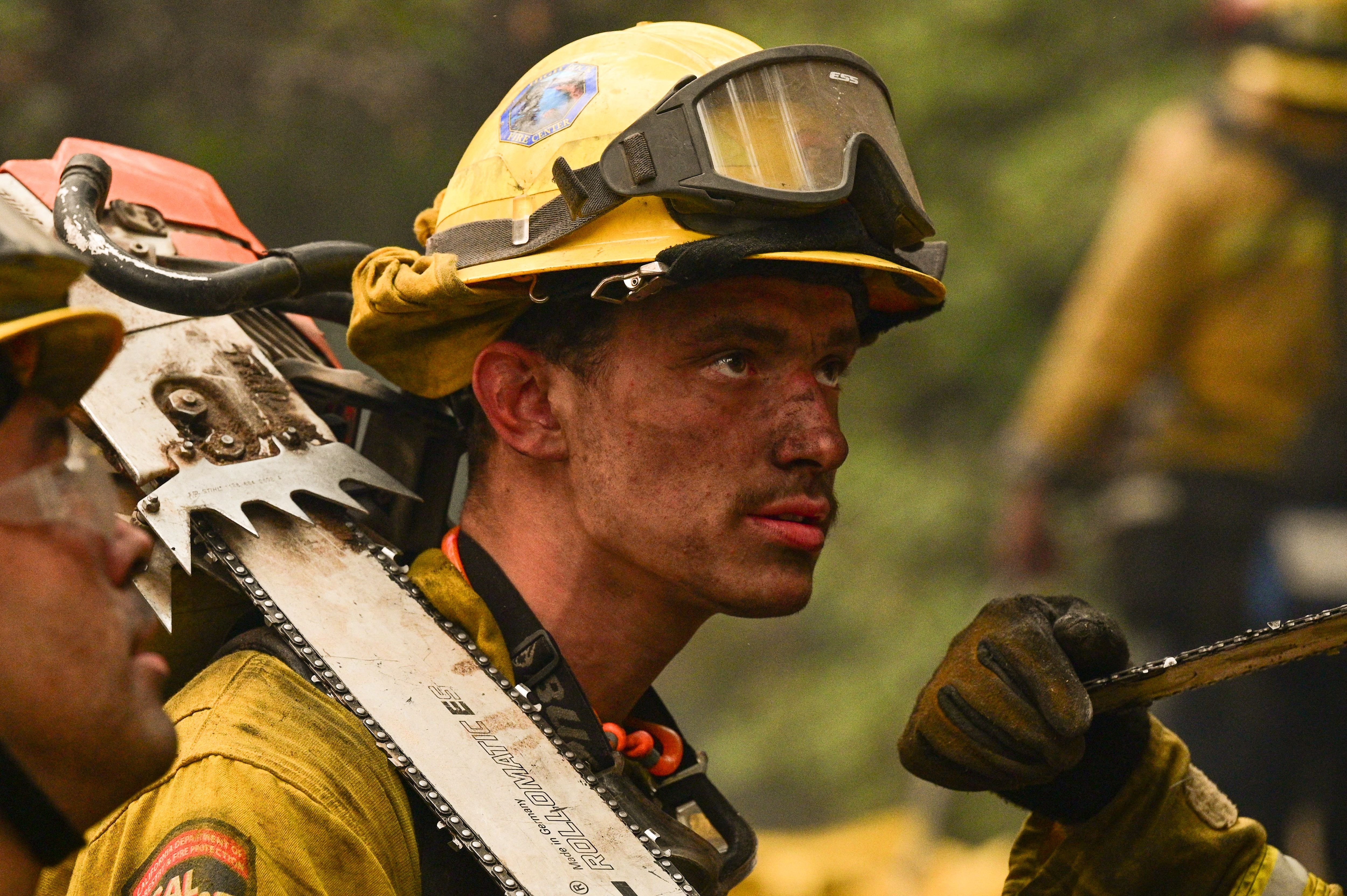 Equipos de bomberos apagaron puntos calientes cerca de cabañas rústicas de montaña en una ladera en Dixie Fire, en Twain, California, el 26 de julio de 2021.