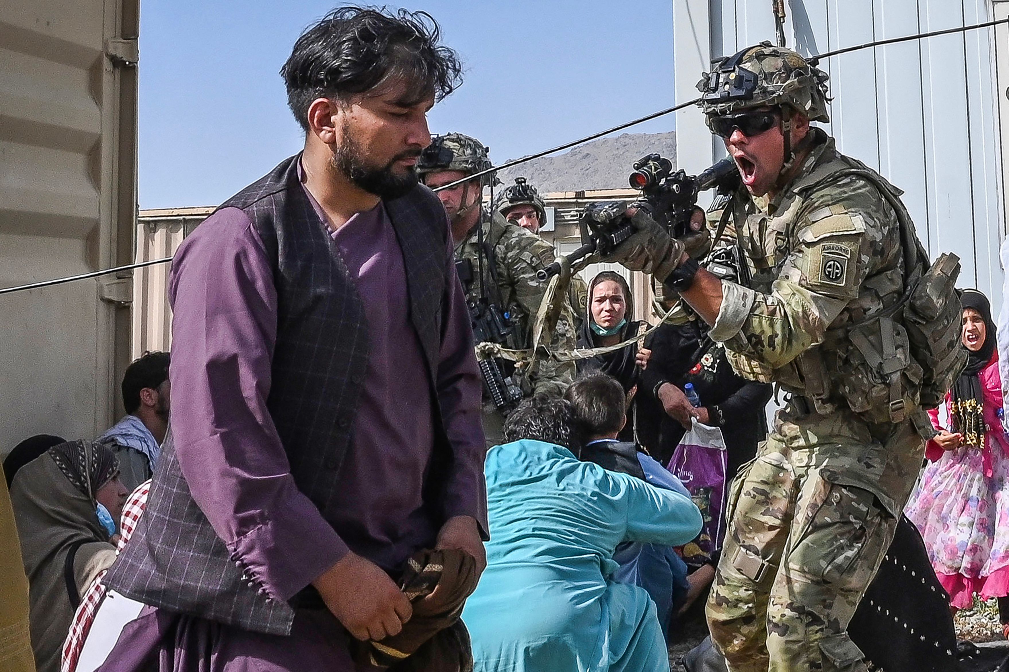 Un soldado estadounidense (C) apuntó su arma hacia un pasajero afgano en el aeropuerto de Kabul en Kabul el 16 de agosto de 2021, después de un final asombrosamente rápido de la guerra de 20 años de Afganistán, mientras miles de personas asaltaban el aeropuerto de la ciudad tratando de huir del grupo.