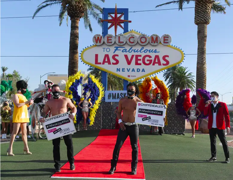 Los miembros del elenco de Chippendales, Ryan Worley (izquierda) y Ricky Rodgers, participan en un desfile de modas frente al letrero Welcome to Fabulous Las Vegas en el Strip de Las Vegas para dar inicio a la campaña profesional de uso de máscaras "Mask Up for Nevada" puesta por Experience. Strategy Associates en medio de la propagación del coronavirus el 25 de junio de 2020 en Las Vegas, Nevada.