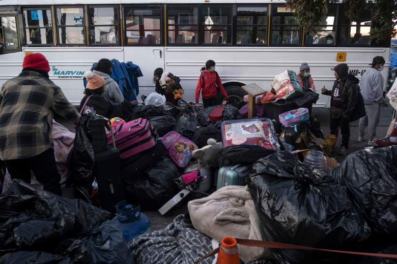 Migrantes se reúnen con sus pertenencias junto a un autobús mientras las autoridades desmantelan un campamento improvisado frente al puerto de cruce de El Chaparral en Tijuana, estado de Baja California, México, cerca de la frontera con EE. UU., el 6 de enero de 2022.