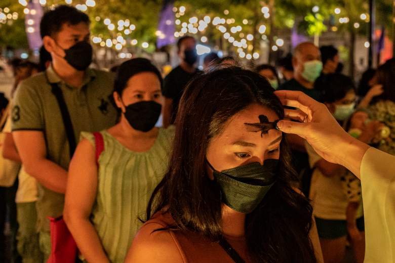 Los filipinos participan en una misa del Miércoles de Ceniza mientras la Catedral de Manila se ilumina con los colores de la bandera de Ucrania el 2 de marzo de 2022 en Manila, Filipinas.