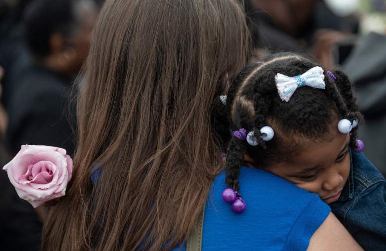 Una niña abraza a su madre y sostiene una rosa durante una ceremonia de dedicación del suelo para las víctimas de la Masacre de Tulsa de 1921, en Stone Hill en el aniversario de 100 años en Tulsa, Oklahoma, el 31 de mayo de 2021.