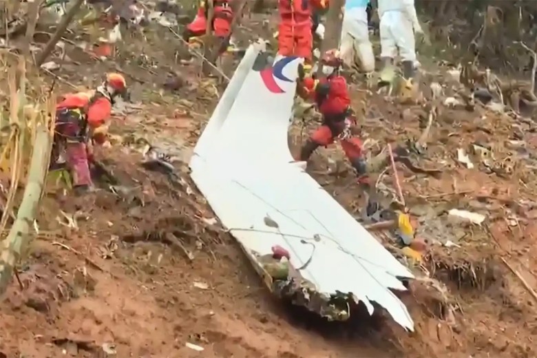 Esta captura de pantalla tomada el 24 de marzo de 2022 de un video de la emisora estatal China Central Television (CCTV) a través de AFPTV muestra a los equipos de rescate con una pieza del fuselaje mientras continúan su búsqueda en el lugar donde un avión de pasajeros de China Eastern se estrelló contra la ladera de una montaña cerca de Ciudad de Wuzhou en la región sur de Guangxi en China.