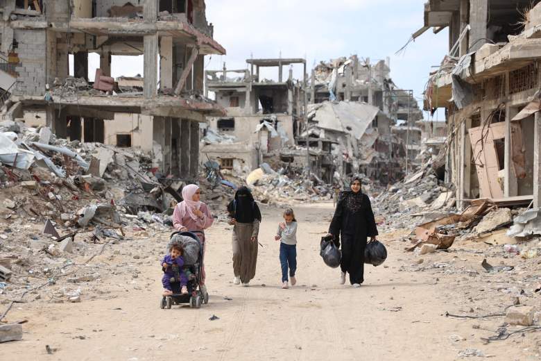 Mujeres y niños palestinos caminan por un camino de tierra bordeado de escombros de construcción en el barrio de Shujaiya de la ciudad de Gaza el 7 de octubre de 2024, en el primer aniversario de la guerra en curso en la Franja de Gaza entre Israel y el grupo palestino Hamas.